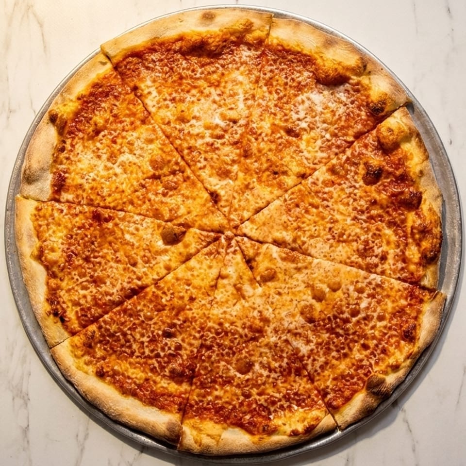 A whole cheese pizza, cut into eight slices, on a metal pan atop a white marble surface.